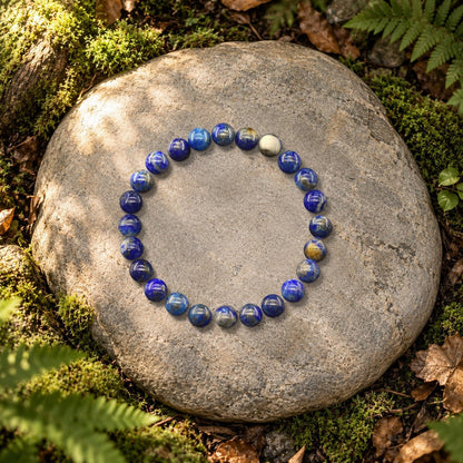 Halo lapis lazuli bracelet with natural stone beads, resting on a rock in the forest