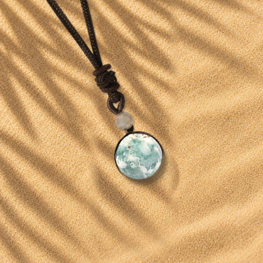 Collier agate mousse Orbe, pendentif sphère en pierre naturelle posé sur le sable