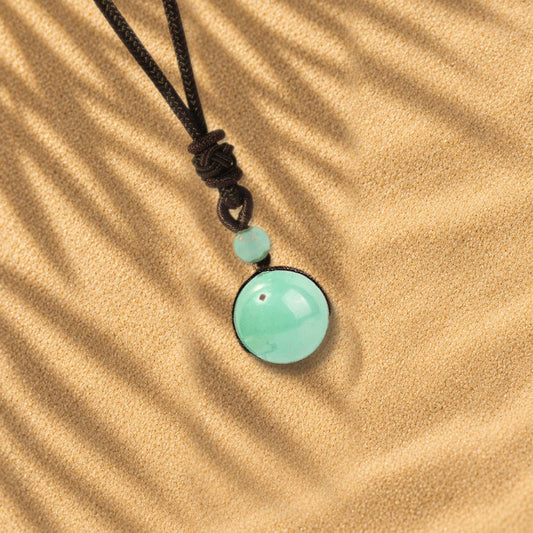 Collier aventurine verte Orbe, pendentif sphère en pierre naturelle posé sur le sable